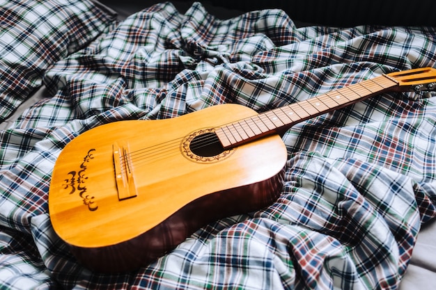 Wooden acoustic guitar on the bed.