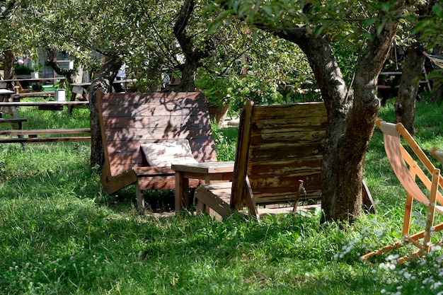 Деревянные кресла и стол в яблоневом саду в кафе под открытым небом в яркий солнечный летний день
