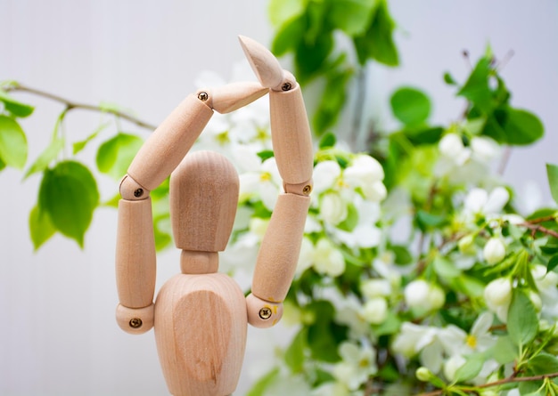 wooden articulated doll hands at the top, dance element, on a background of greenery.