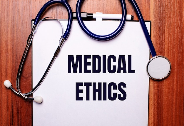 Su uno sfondo di legno si trova uno stetoscopio e un foglio di carta con la scritta medical ethics. disposizione piatta. concetto medico