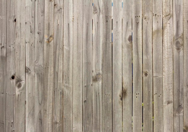 Деревянный фон. Старый деревянный забор из неокрашенных досок с трещинами и гвоздями.