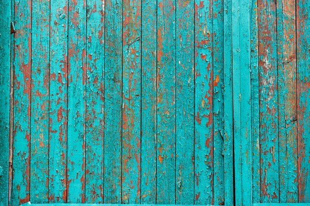 Wooden background painted in turquoise color Cracked turquoise paint Old paint on the fence