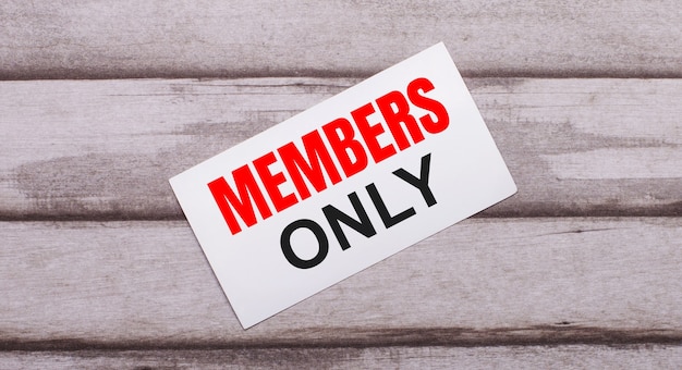 On a wooden background, there is a white card with red text MEMBERS ONLY