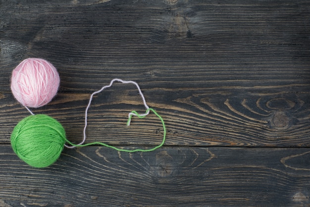 Photo on a wooden background, two balls of pink and green thread