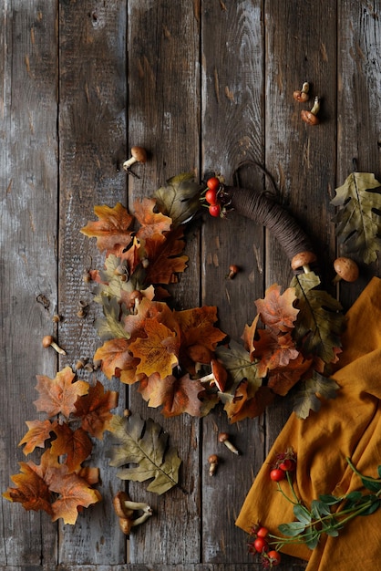 wooden background with autumn wreath from leaves mushrooms berries and textile toy