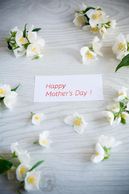 Foto fondo in legno con bellissimo gelsomino bianco in fiore e congratulazioni per la madre