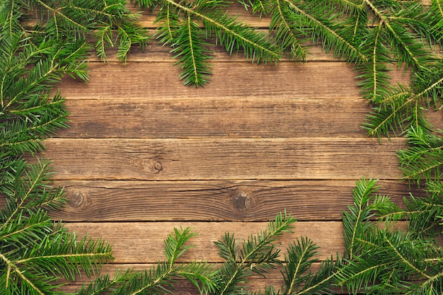 Wooden background with fir branches on the edge.