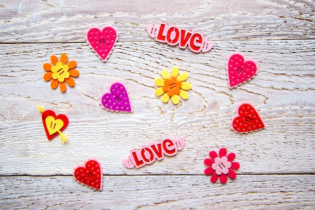 Wooden background with hearts, flowers and the word LOVE on Valentine's day