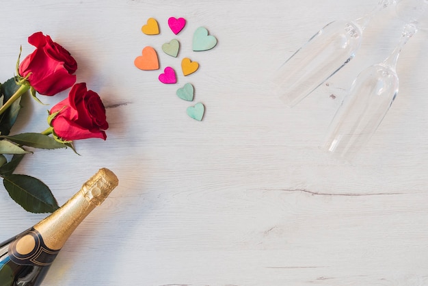 Wooden background with roses, hearts, glasses of champagne, champagne, copy space