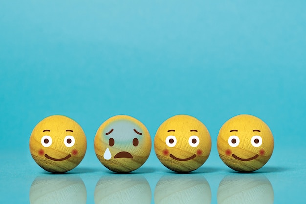 Photo wooden balls as emoticons with different emotions on blue background