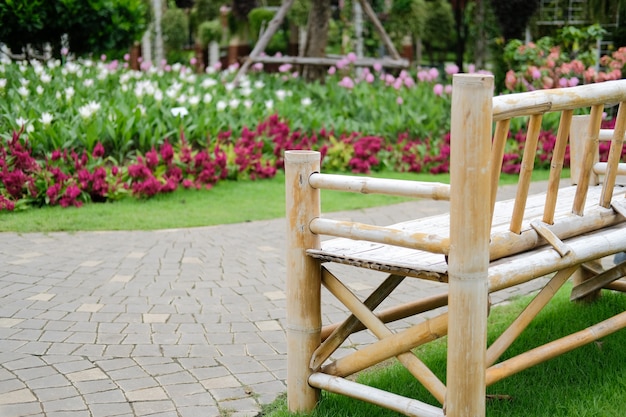 Foto banco di bambù di legno in giardino floreale