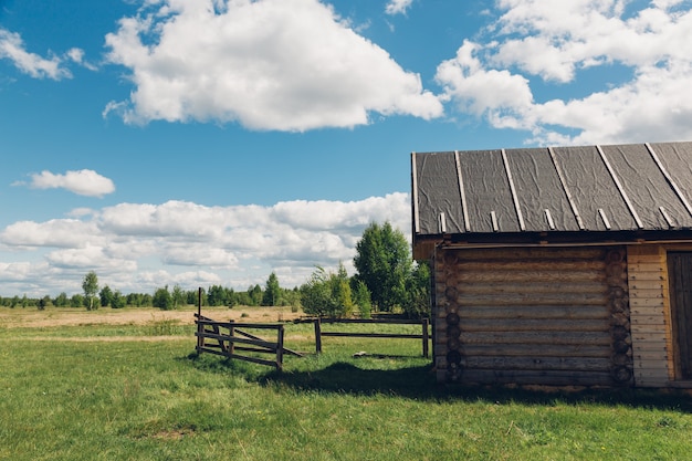 Wooden barn with a wooden ladder on the background of field