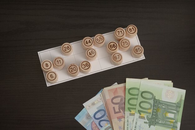 Wooden barrels lotto, cards and euro. Black wooden table.