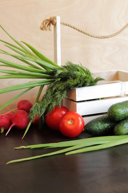 新鮮な野菜が入った木製のバスケット 木のテーブルの上のバスケットに入った新鮮な野菜の束