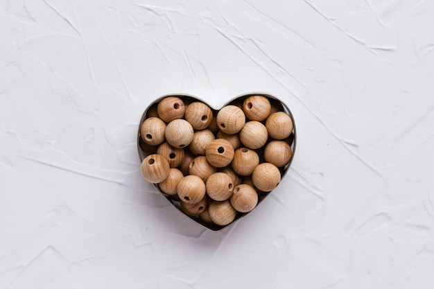 Wooden beads in shape of heart for baby teether on white background Natural handmade wood toy for child Ecofriendly children toy Top view flat lay