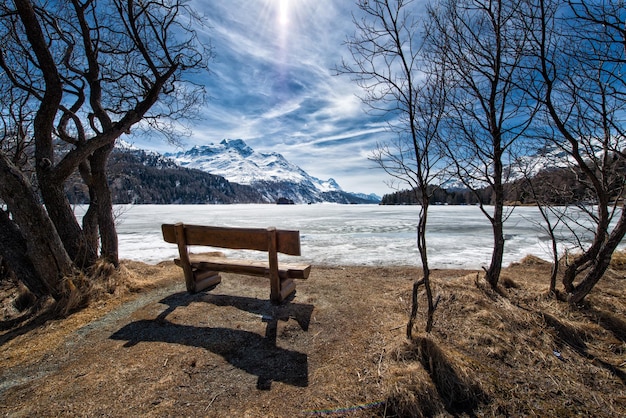 Wooden bench to admire the scenery on an alpine lake ice