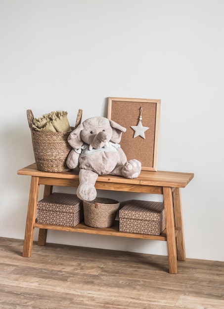 Wooden bench basket with blankets stuffed elephant toy in the\
interior of the children\'s room