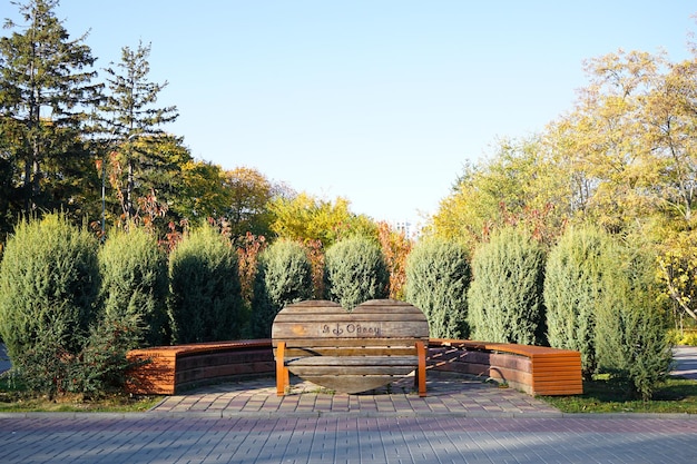 Wooden bench in the form of a heart in the Odessa autumn park with space for text