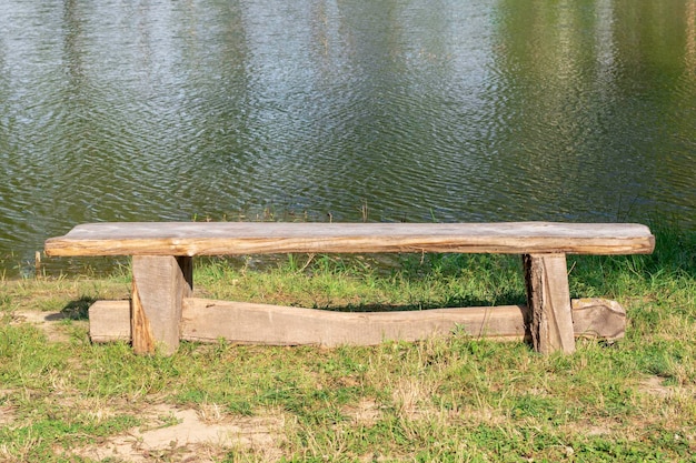 A wooden bench near a pond at daytimeBeautiful view of the lakeThe concept of outdoor recreation