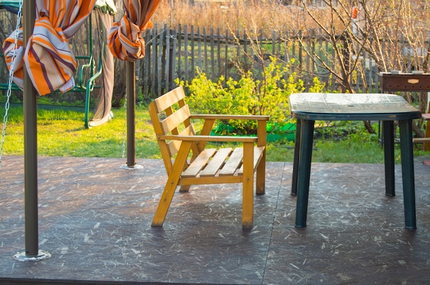 Panca in legno e tavolo verde in plastica sulla veranda in una casa di campagna, all'inizio della primavera, all'aperto