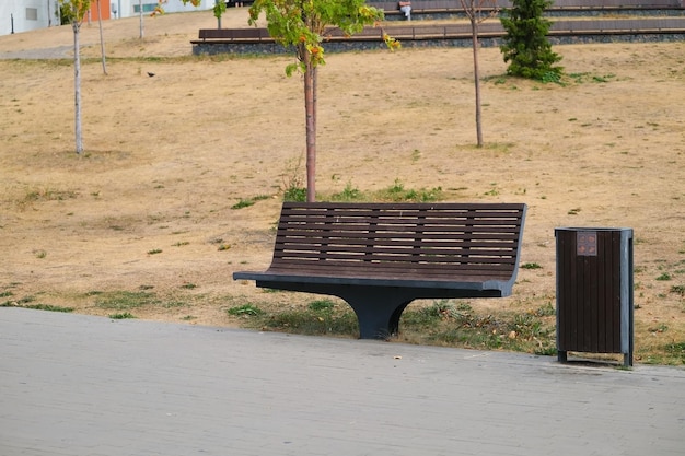 Wooden bench and a trash can for separate waste collection stand in the park