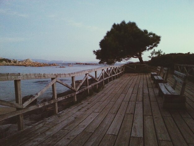 Wooden benches on shore against sky