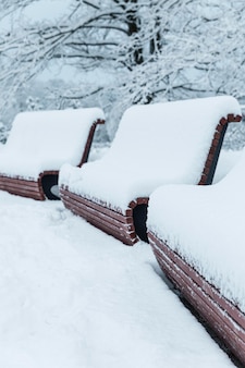 Panche in legno sotto lo spessore della neve nel parco. una bella favola invernale. verticale.
