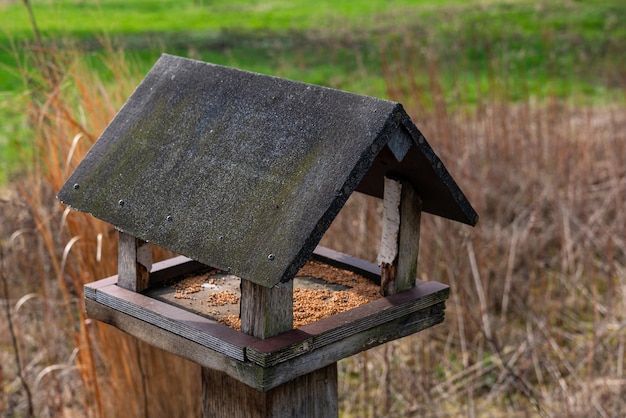 Wooden bird feeder with a houseshaped roof close up