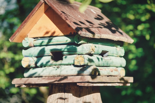 Wooden birdhouse in the form of a house on blurred trees background