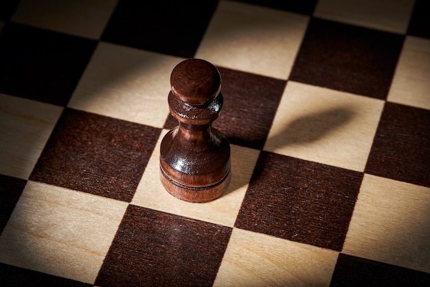 Wooden black pawn on a chessboard, the concept of strategy, planning and decision-making