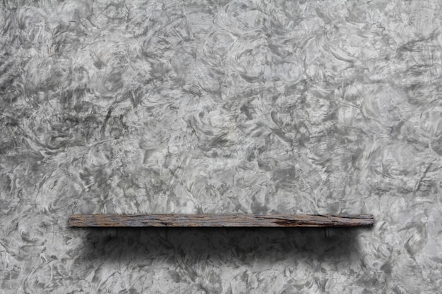 Wooden blank book shelf on interior gray cement wall.