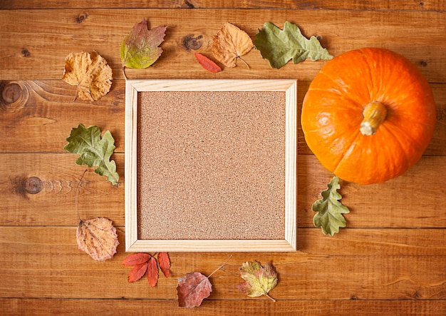 wooden blank tablet with dry autumn leaves and pumpkin