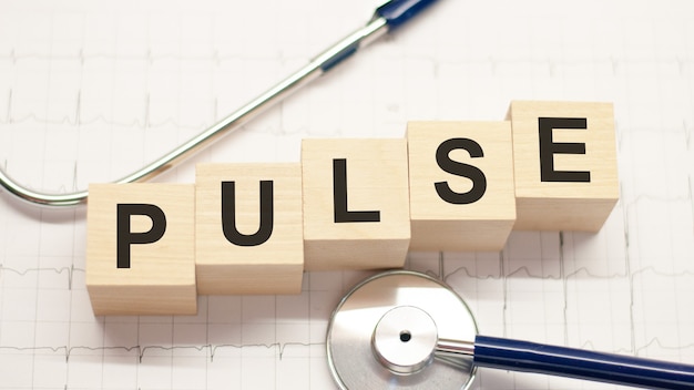 Деревянный блок формирует слово пульс с помощью стетоскопа на рабочем столе врача. концепция здравоохранения для больниц, клиник и медицинского бизнеса