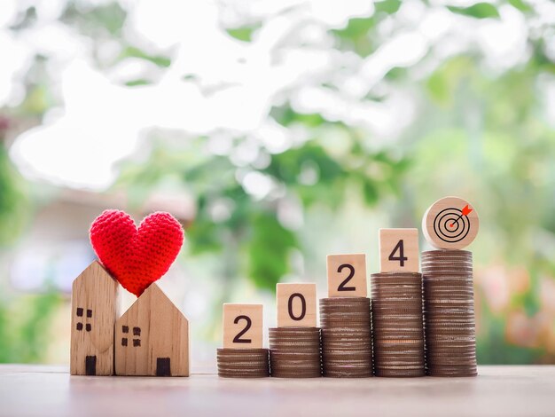 Photo wooden block with 2024 and goal business icon miniature house on stack of coins the concept of property investment house mortgage real estste