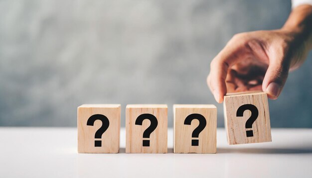 Wooden block with question mark on white table against blank wall symbolizing uncertainty and searc