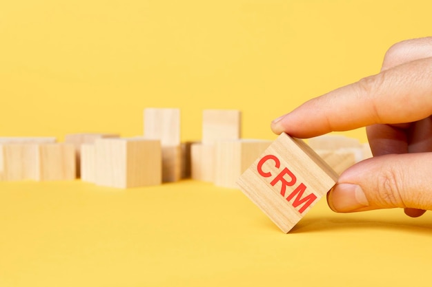 Wooden block with text CRM on yellow background