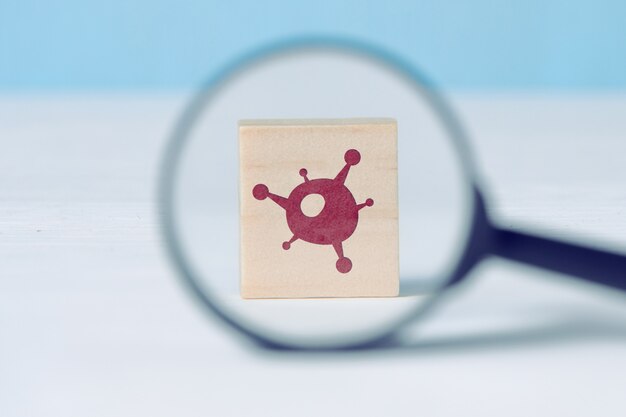 Wooden block with a virus icon under a magnifying glass.