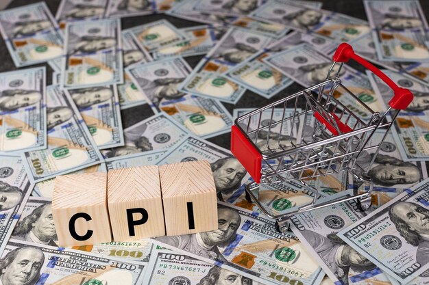 Wooden block with the word cpi and an empty shopping cart on a banknotes of dollar background Business and CPI consumer price index concept