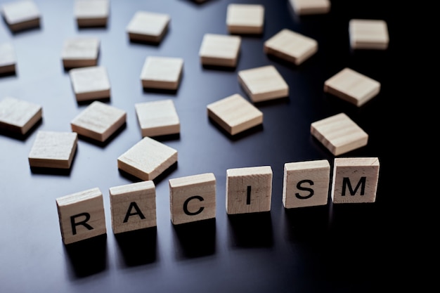 Wooden block with word racism on the black background