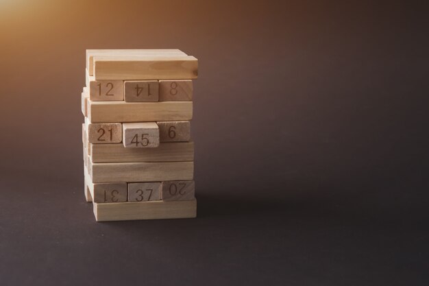 Wooden blocks folded into the tower with sunshine on brown background. Success, growth