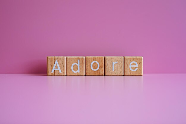 Photo wooden blocks form the text adore against a pink background