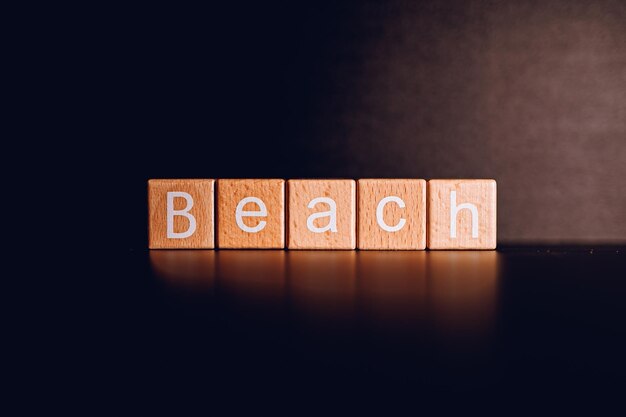 Photo wooden blocks form the text beach against a black background