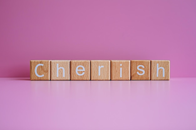 Wooden blocks form the text Cherish against a pink background