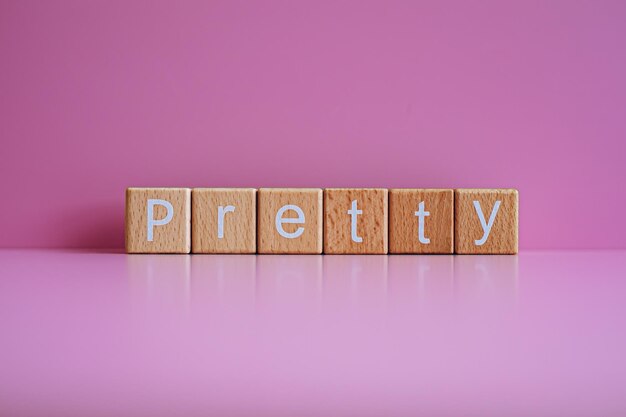 Wooden blocks form the text Pretty against a pink background