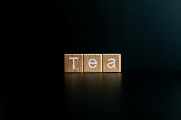 Photo wooden blocks form the text tea against a black background