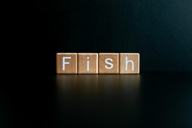 Фото Деревянные блоки образуют текст рыба на черном фоне