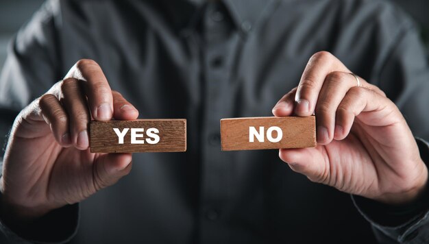 Фото Деревянные блоки, удерживаемые руками бизнесмена, изображают да и нет, изображая принятие решений выбор означает успех в бизнесе думайте с выбором да или нет