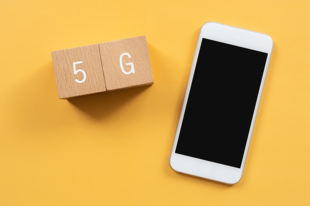 Wooden blocks with 5G text of concept and a mobile phone.