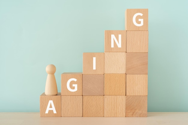 Wooden blocks with AGING text of concept and a human toy.