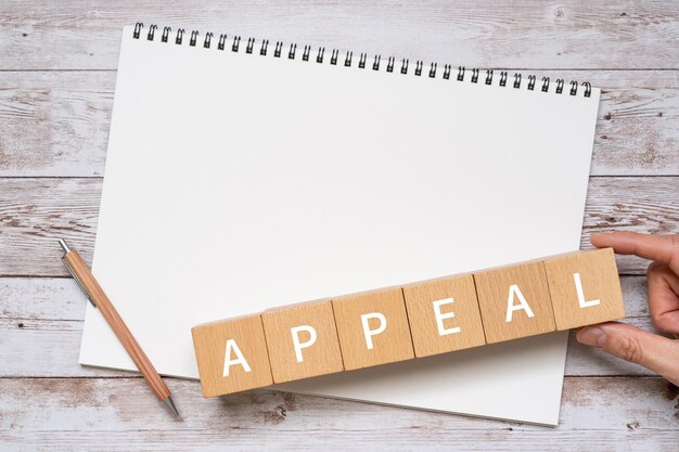 Wooden blocks with APPEAL text of concept, a pen, and a notebook.